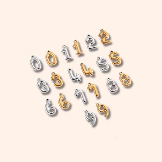 Set of number charms in gold and silver on a beige background