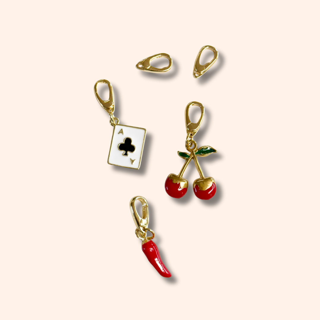 Set of gold and red charm clips on a beige background