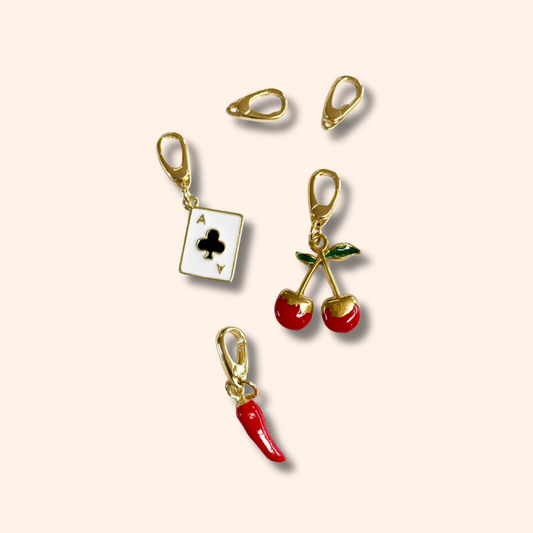 Set of gold and red charm clips on a beige background