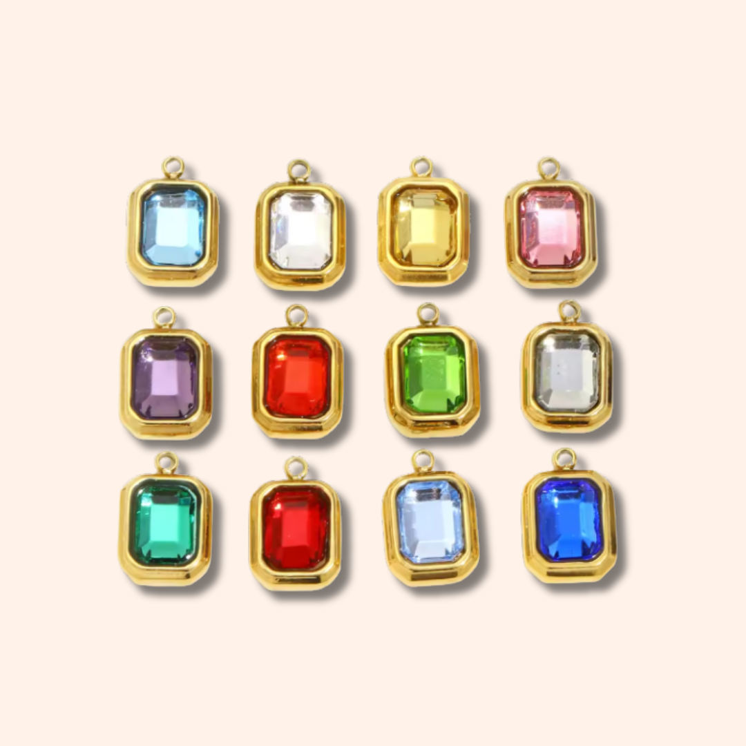 Gold-framed gemstone pendants in various colors on a beige background