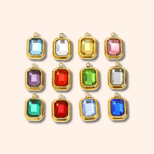 Gold-framed gemstone pendants in various colors on a beige background
