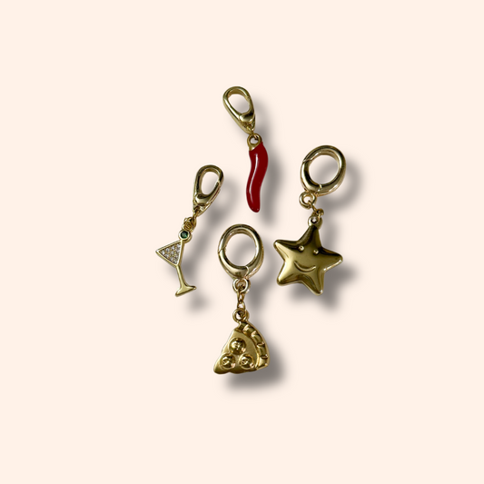 Set of gold charms including a martini glass, pizza slice, and star on a beige background