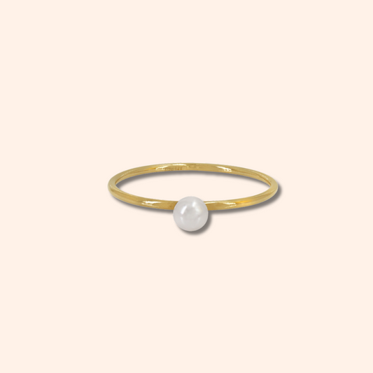 Gold ring with a pearl on a beige background