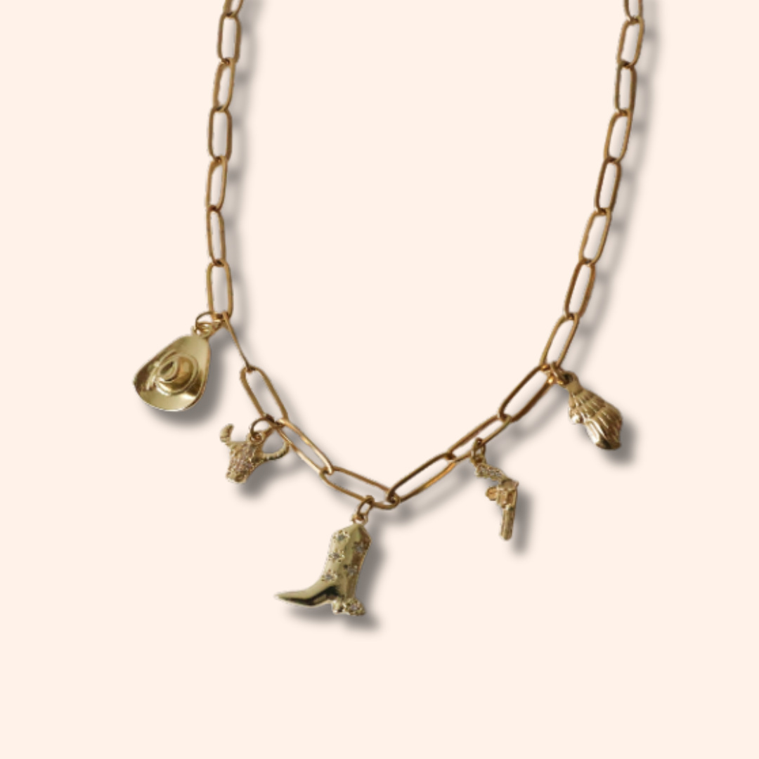 Gold necklace with various charms on a beige background
