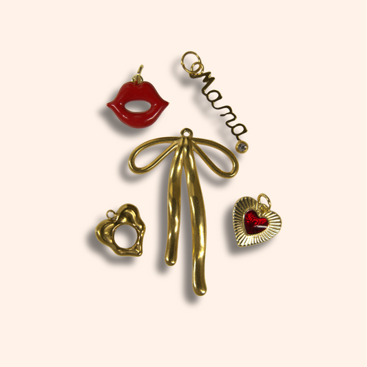 Gold bow-shaped pendant with heart and lip charms on a beige background