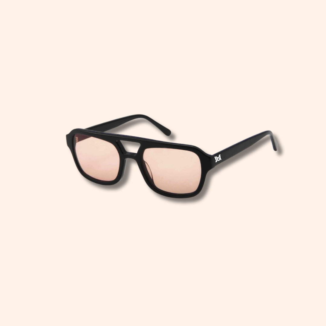 Black sunglasses with pink lenses on a beige background