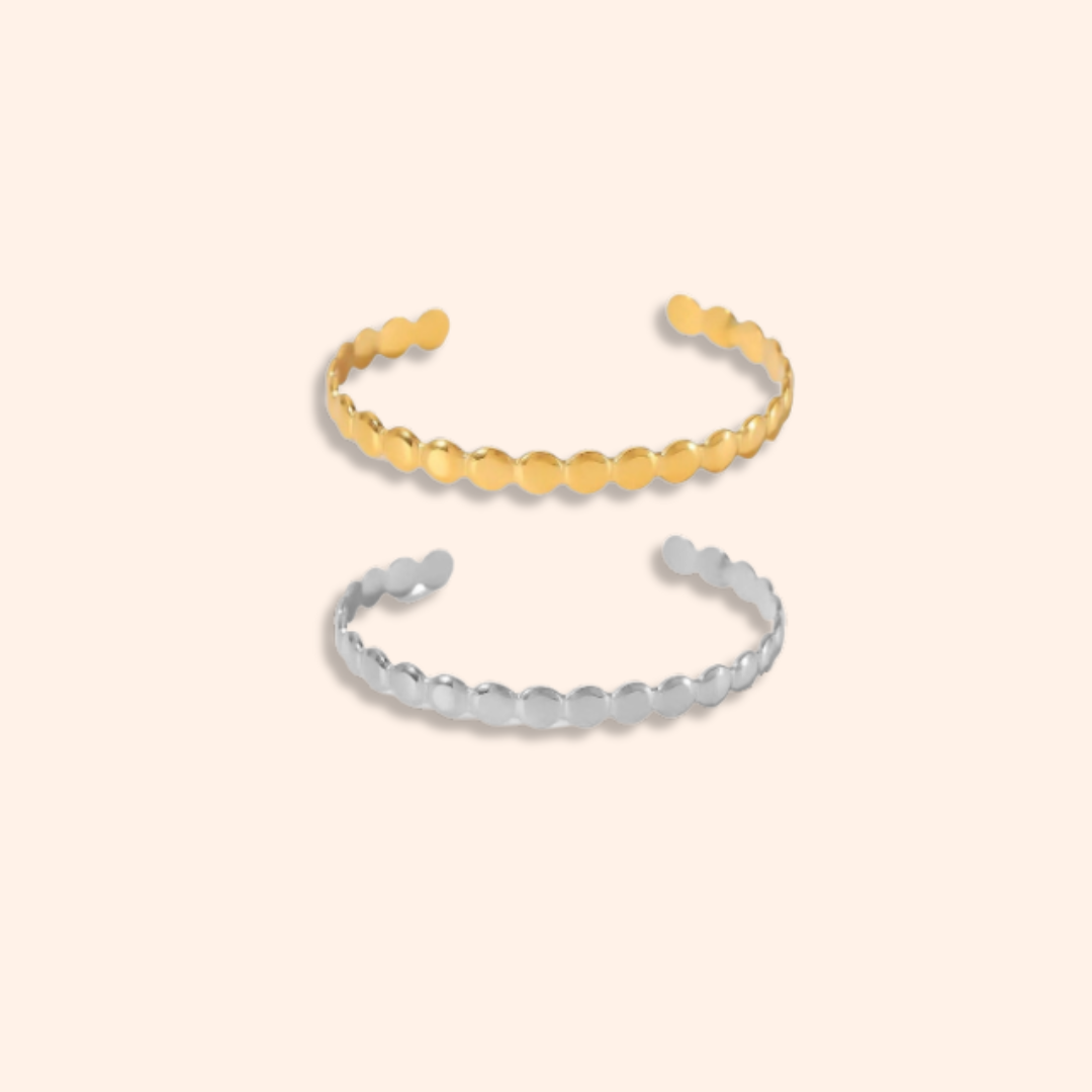 Two gold and silver bangle bracelets on a beige background