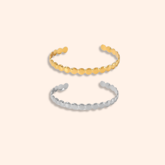 Two gold and silver bangle bracelets on a beige background