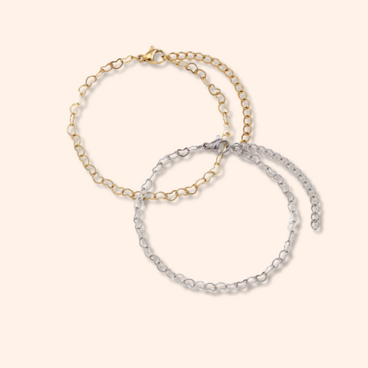 Two gold and silver chain bracelets on a light beige background
