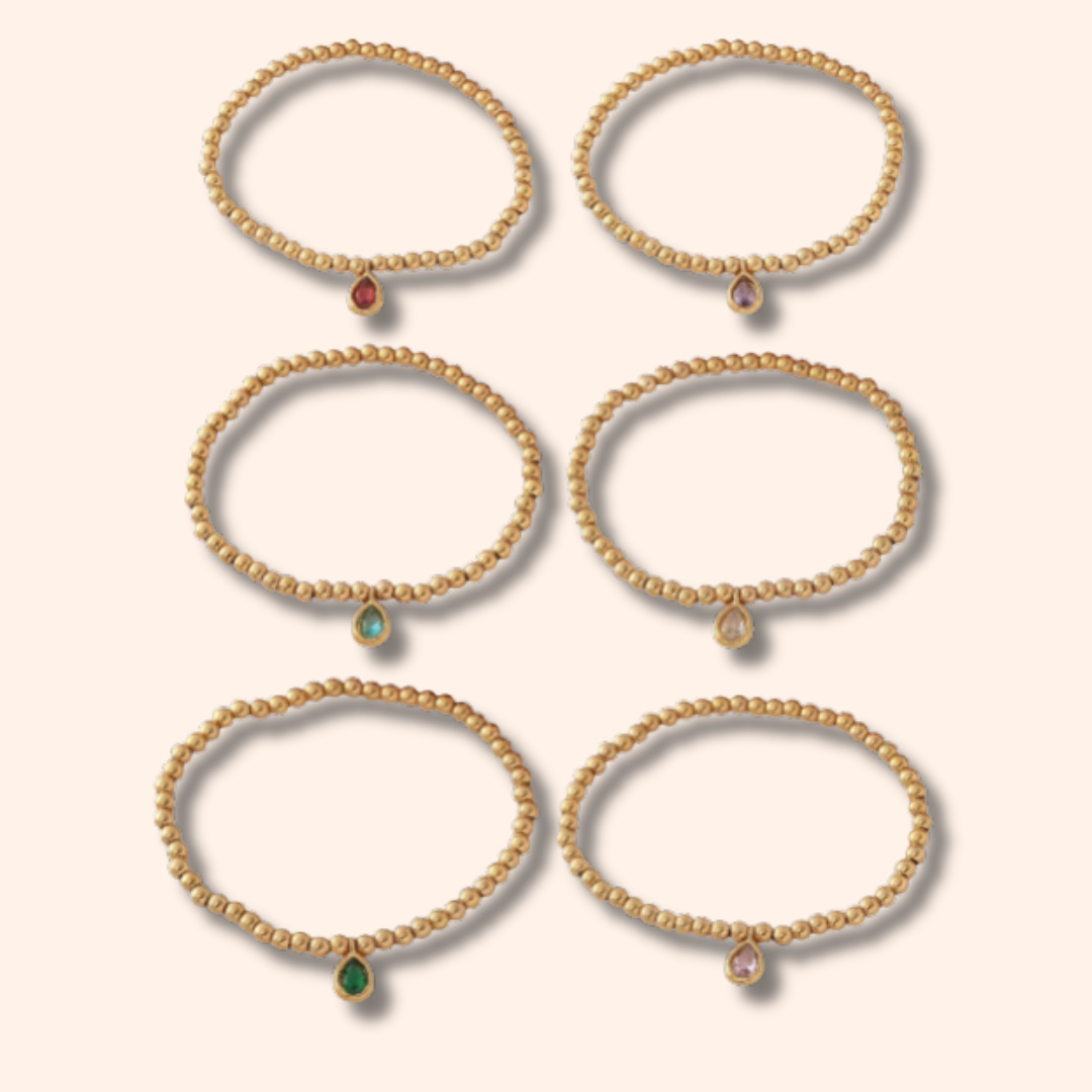 Set of gold bracelets with gemstones on a beige background