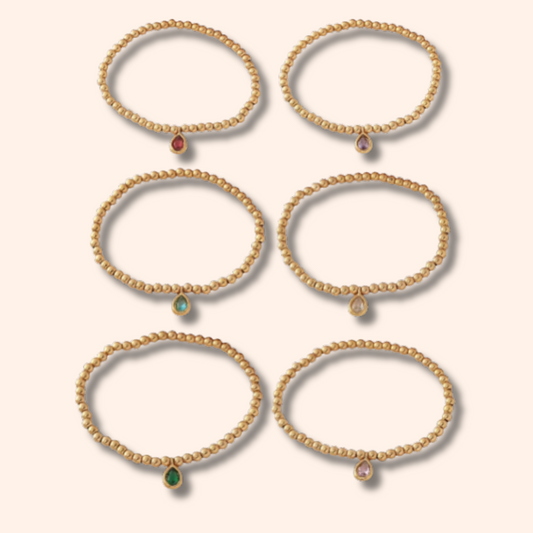 Set of gold bracelets with gemstones on a beige background