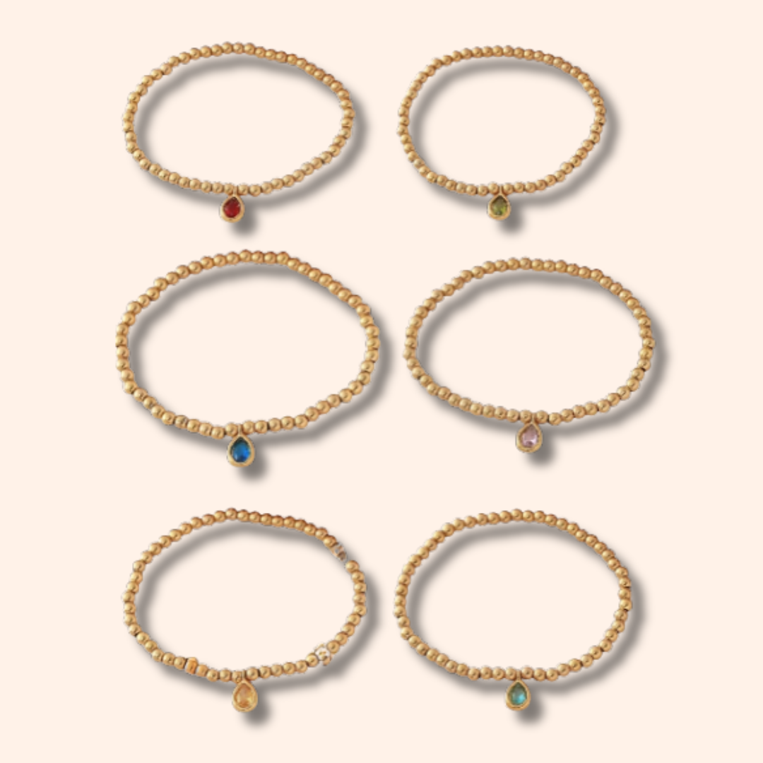 Set of gold bracelets with gemstones on a beige background
