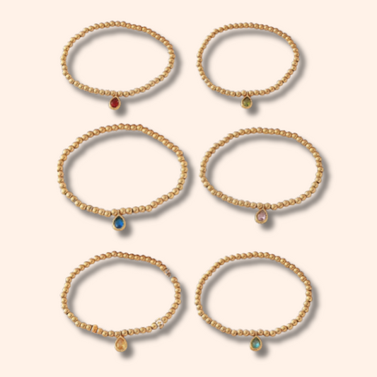 Set of gold bracelets with gemstones on a beige background