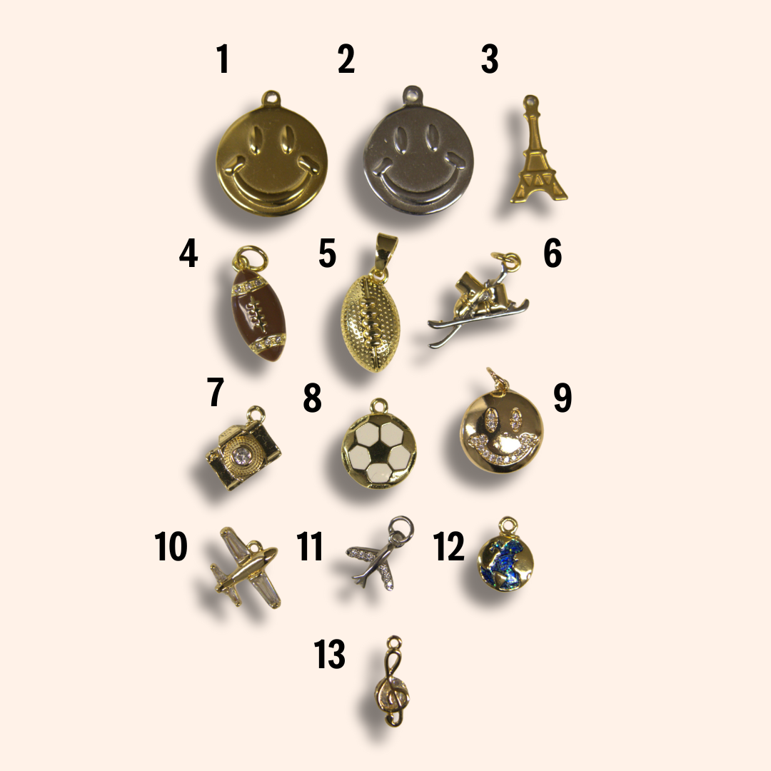 Collection of 13 gold pendants on a beige background