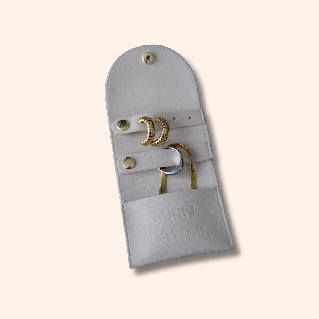 Gray jewelry pouch with gold rings on a beige background