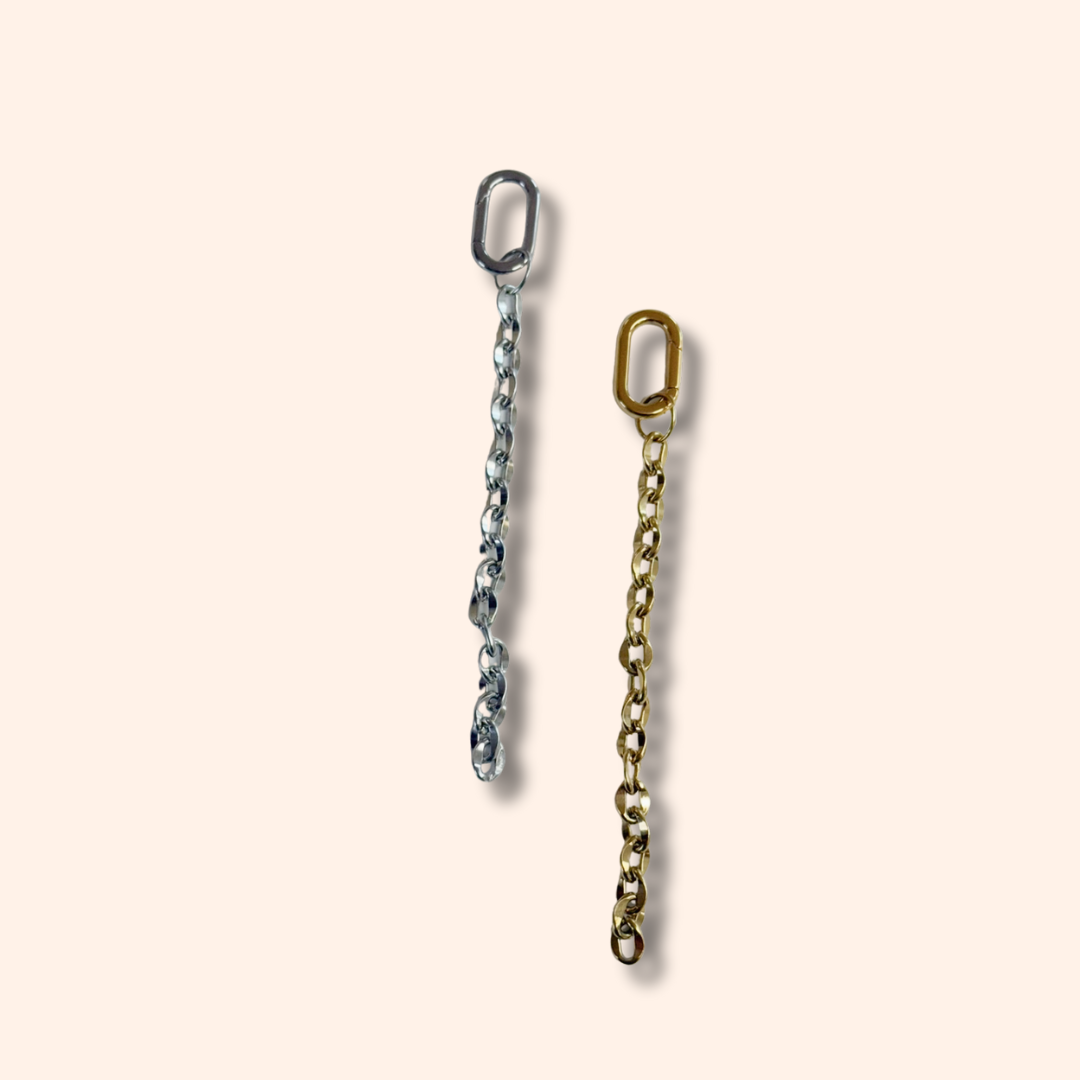 Two earrings with chains on a beige background