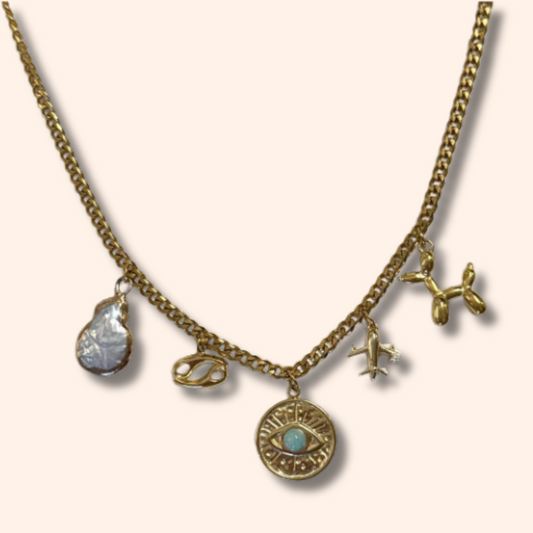 Gold necklace with various charms on a light pink background
