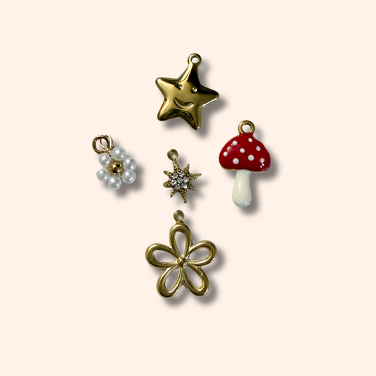 Collection of various charms including a star, mushroom, and flower on a light pink background