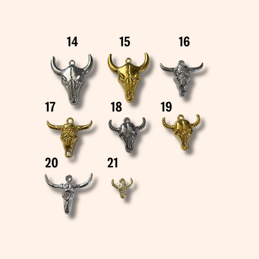 Collection of metal bull head pendants on a beige background