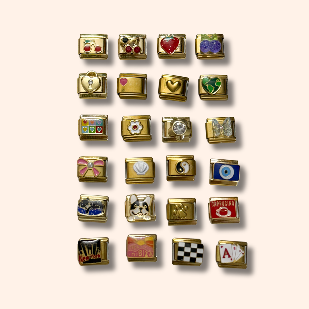Collection of gold charm beads with various symbols on a beige background