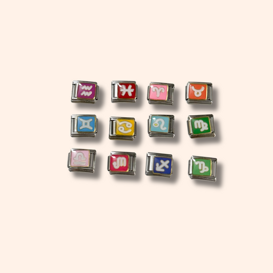 Set of colorful zodiac charm buttons on a light beige background
