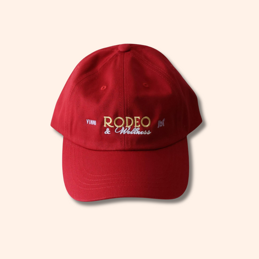Red cap with 'Rodeo & Wellness' text on a beige background