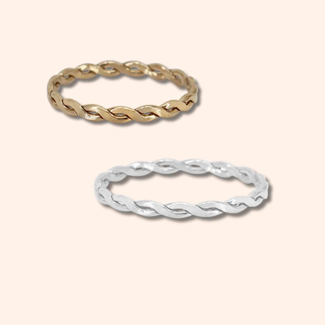 Two gold and silver twisted rings on a light beige background