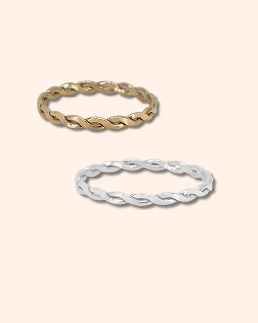 Two gold and silver twisted rings on a light beige background