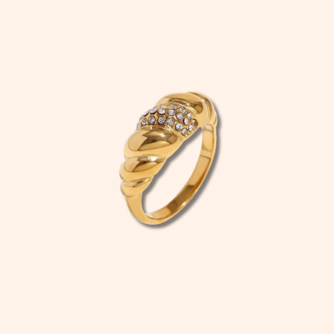 Gold ring with diamond accents on a beige background