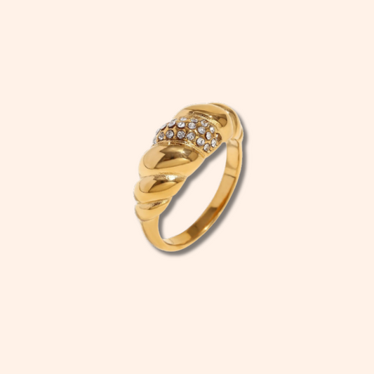 Gold ring with diamond accents on a beige background