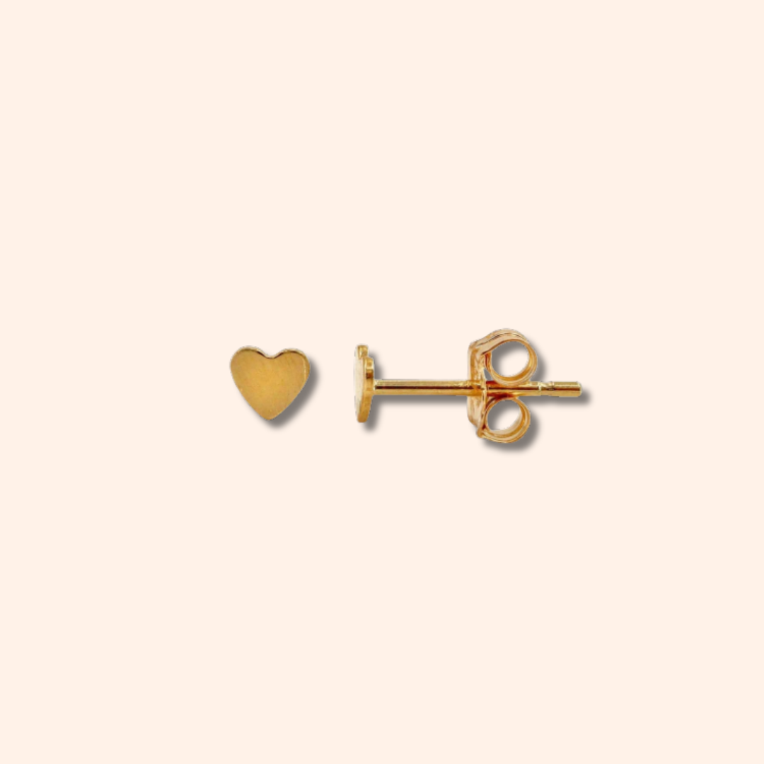 Gold heart-shaped earring on a beige background
