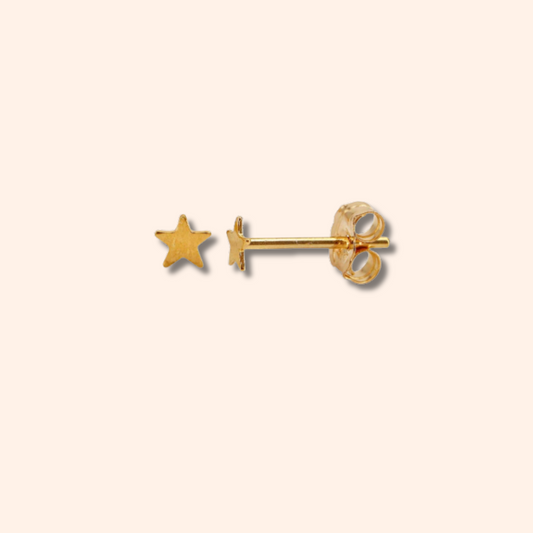 Gold star and circle stud earrings on a beige background
