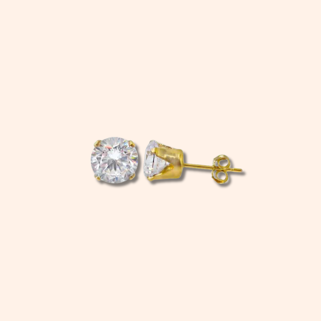 Gold stud earrings with a clear gemstone on a beige background