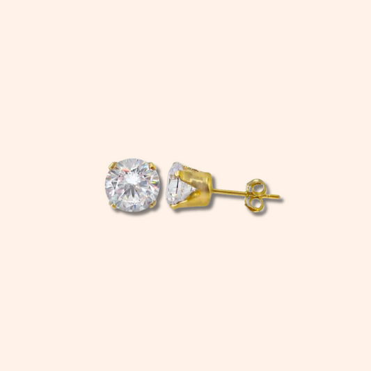 Gold stud earrings with a clear gemstone on a beige background