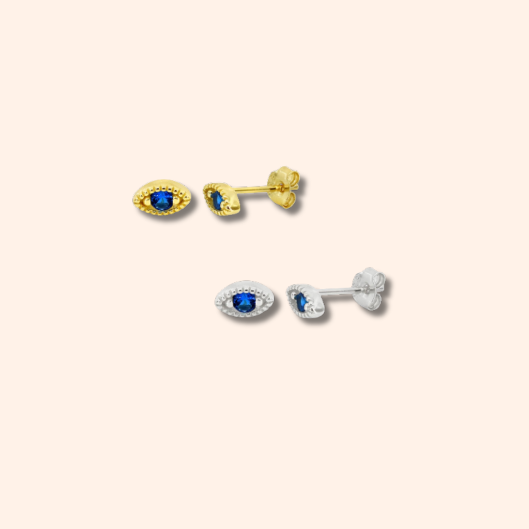 Pair of gold and silver earrings with gemstones on a beige background