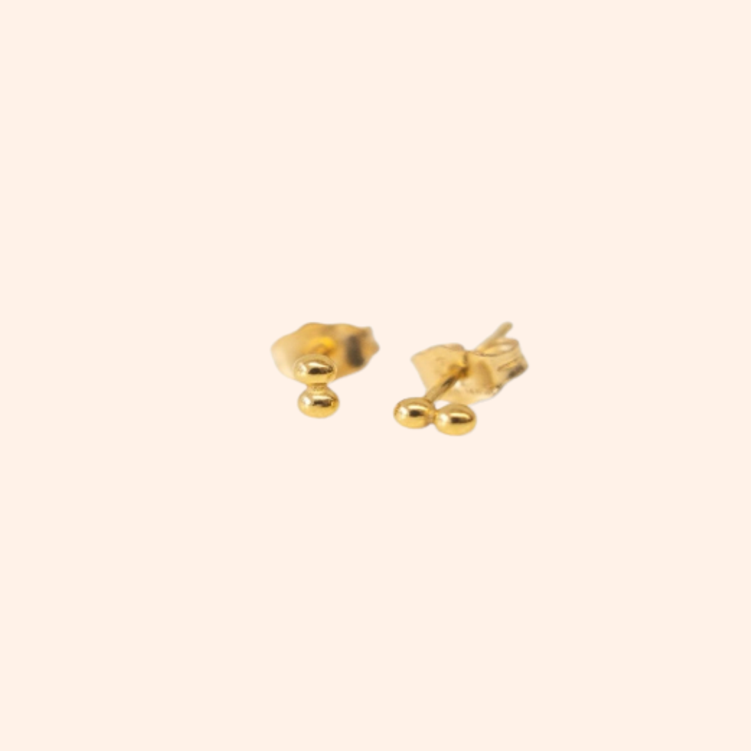 Gold bow-shaped earrings on a light beige background