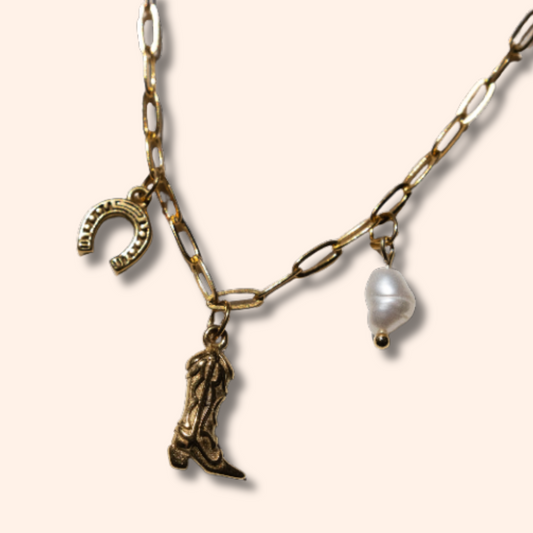 Necklace with cowboy boot, horseshoe, and pearl charm on a beige background