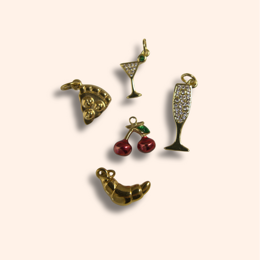 Set of five gold-themed charms on a beige background