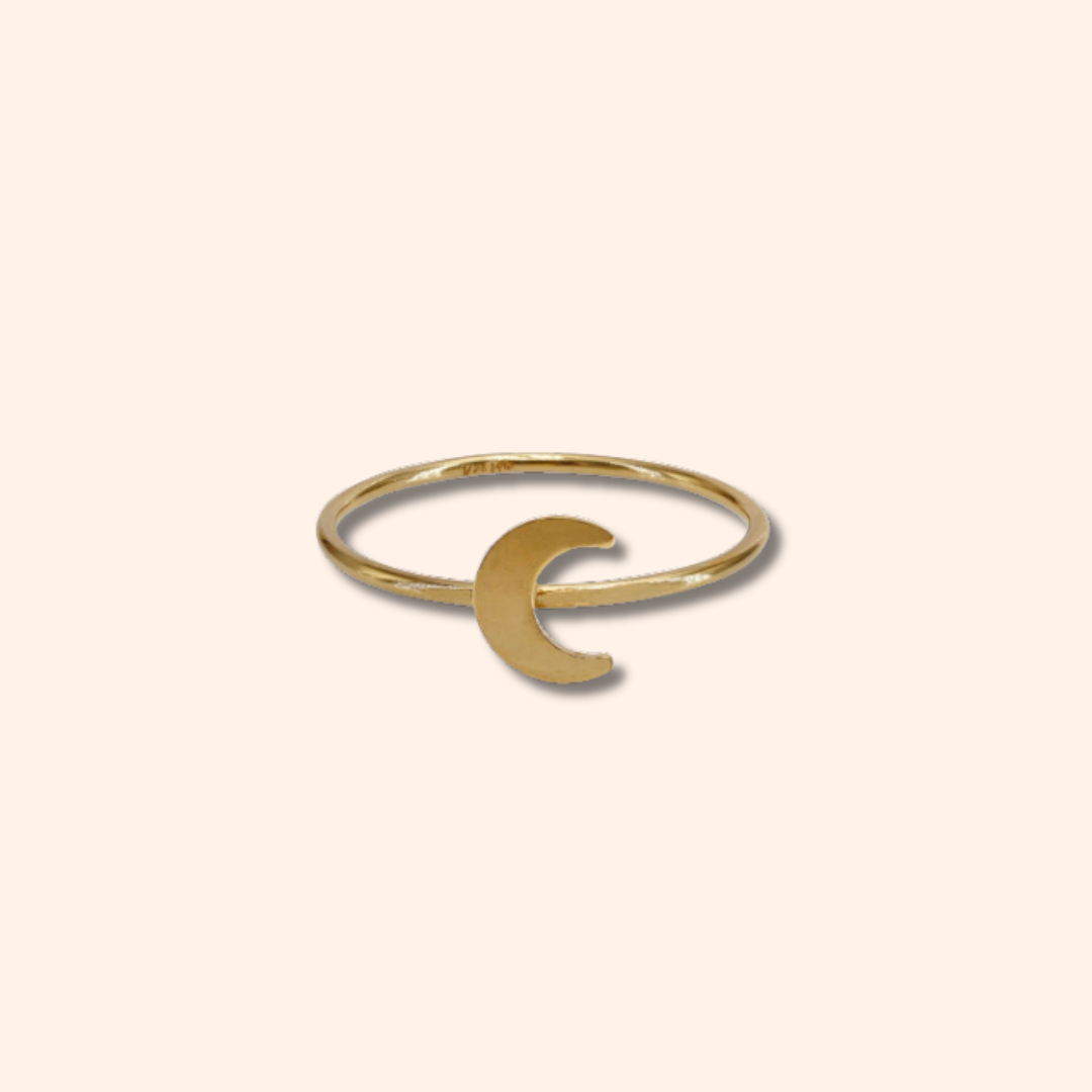 Gold ring with a crescent moon design on a beige background