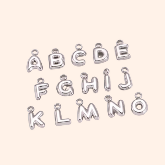 Silver letter charms on a light pink background