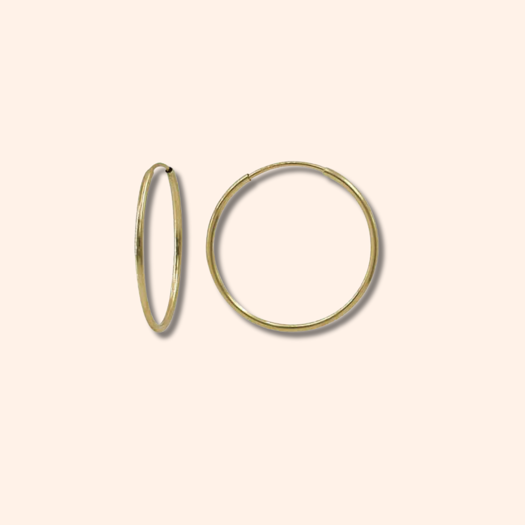 Gold hoop earrings on a beige background