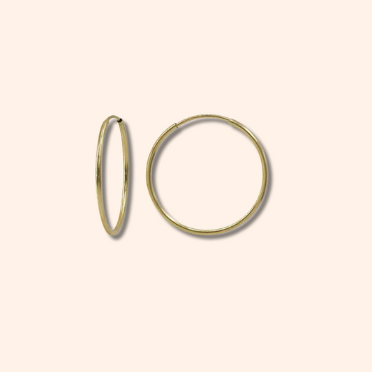 Gold hoop earrings on a beige background