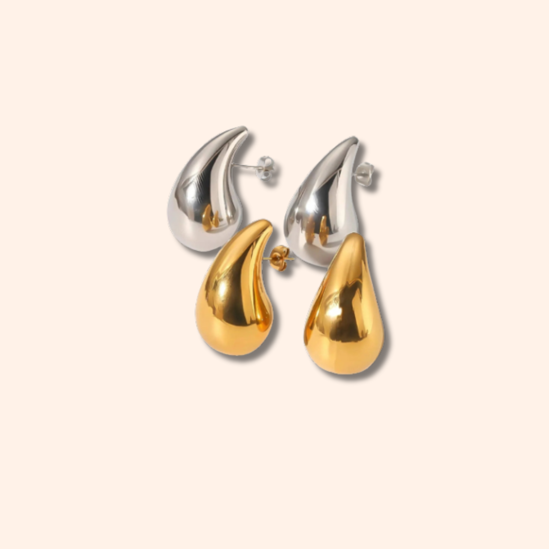 Pair of earrings with gold and silver teardrop design on a beige background