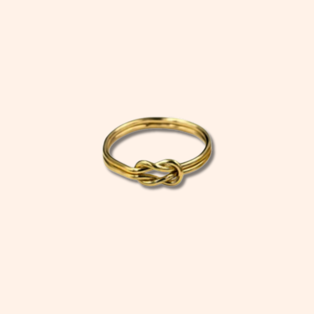 Gold ring with a knot design on a beige background