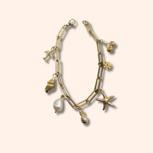 Gold bracelet with various charms on a beige background