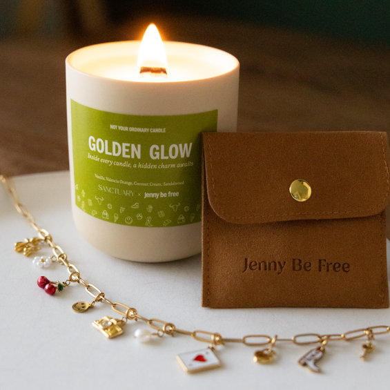 Candle labeled 'Golden Glow' with a brown pouch and jewelry on a white surface