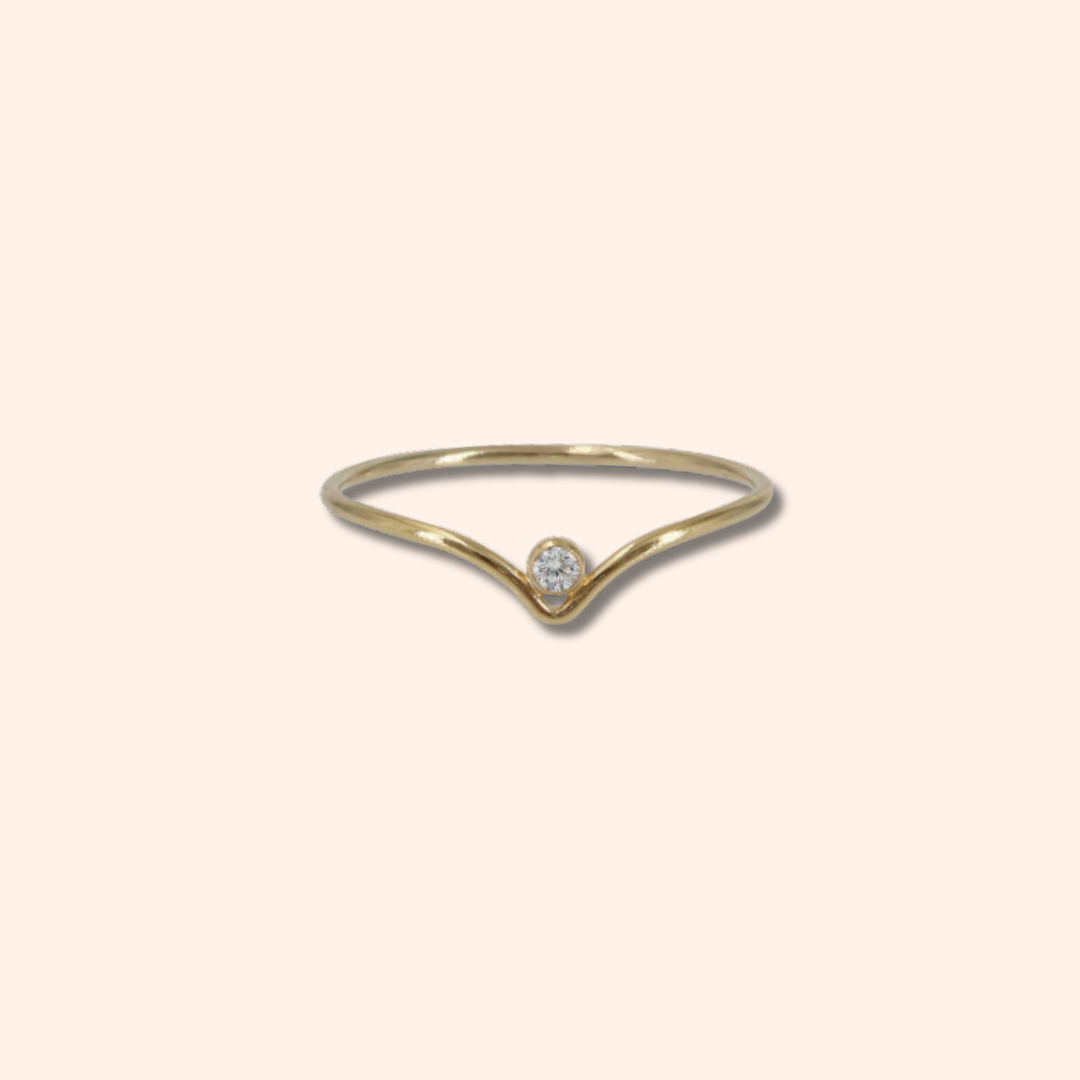 Gold ring with a small diamond on a beige background