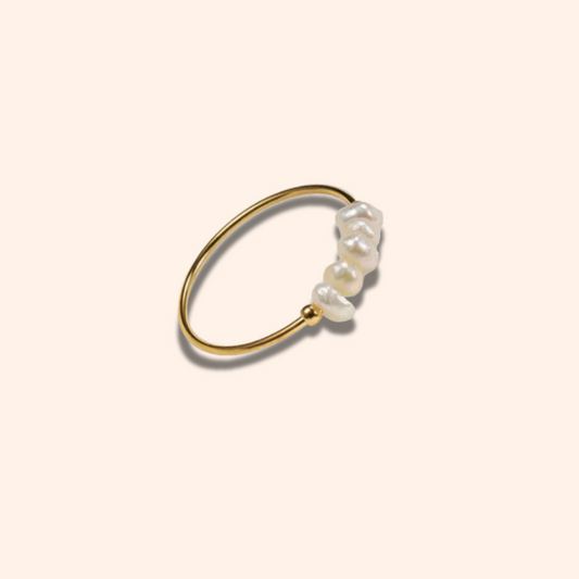 Gold ring with three pearls on a beige background