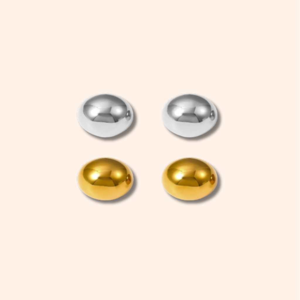 Pair of gold and silver round earrings on a beige background