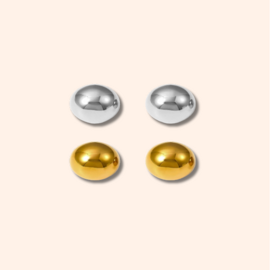 Pair of gold and silver round earrings on a beige background
